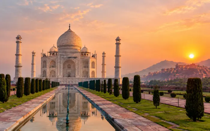 Best Sunrise and Sunset Spots Along the Golden Triangle featuring the Taj Mahal and its reflecting pool under a beautiful sunset sky in Agra, India.